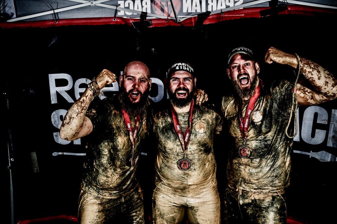 Foto posando con mis hermanos y las medallas después de acabar la Spartan Race